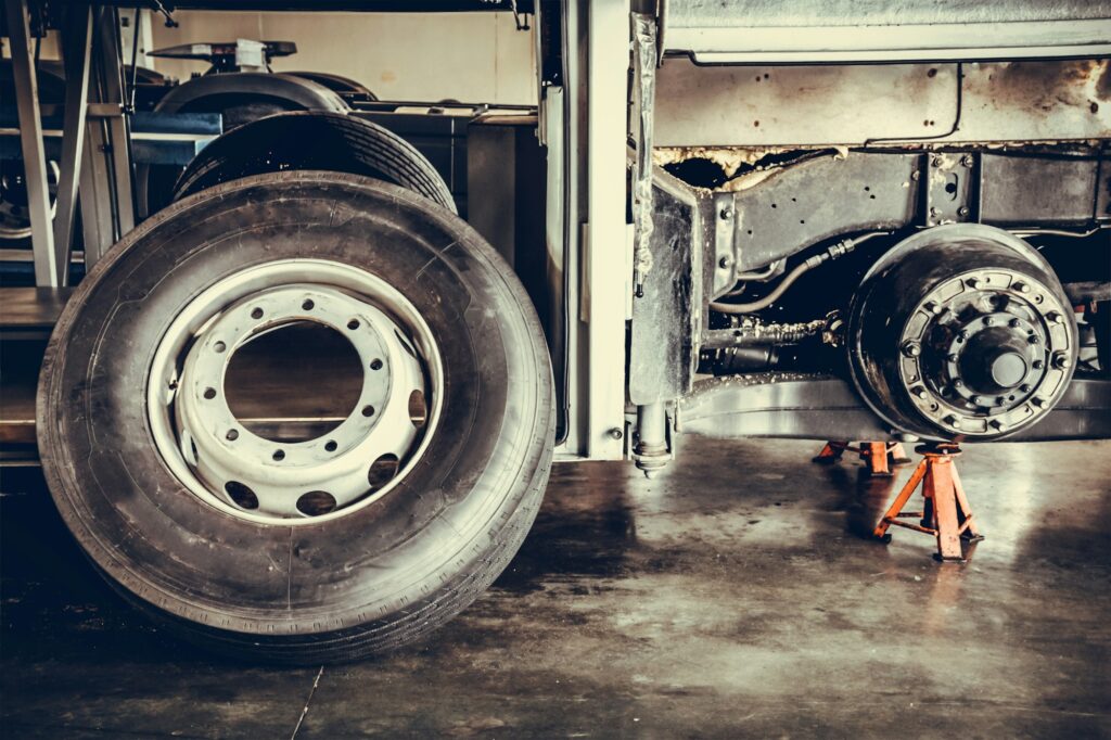 bus spare wheel tire waiting to change and axle bus on the lifting jack at the garage.