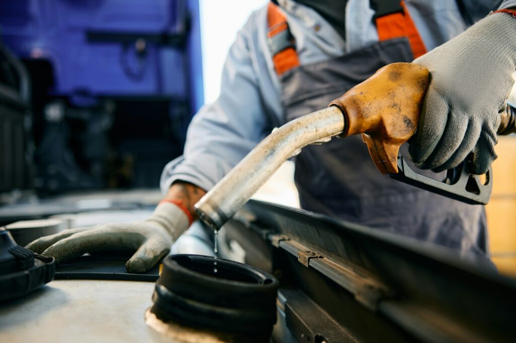 Close up of driver filling truck fuel tank with gasoline.