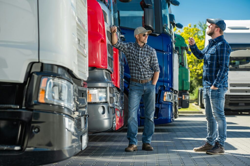 Two Truckers Standing Next to a Row of Semi Trucks